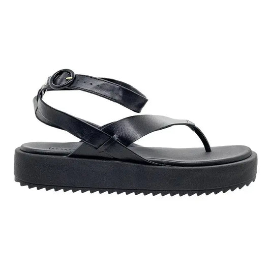 Product shot of a black leather platform sandal with an ankle strap featuring a gold buckle and a textured sole showcasing a unique crisscross design and a sleek silhouette