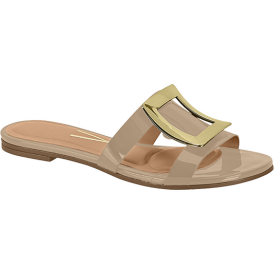 Product shot of a beige patent leather slide sandal featuring a gold-toned buckle with a glossy finish and a cushioned insole.