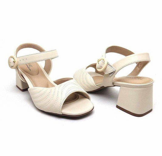 Product shot of a pair of cream-colored Vizzano sandals featuring a unique quilted design,  a gold buckle accent, and a chunky block heel against a white background
