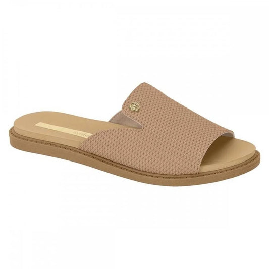 Product shot of a beige Grendene slide sandal featuring a textured woven upper a gold logo and a flat brown sole
