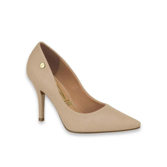 Product shot of a beige suede high-heeled pump with a gold logo detail and pointed toe featuring a slender heel and subtle stitching
