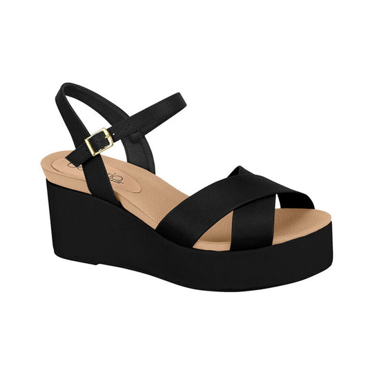 Product shot of a black platform wedge sandal with a crisscross strap and gold buckle featuring a cushioned footbed and a sturdy sole
