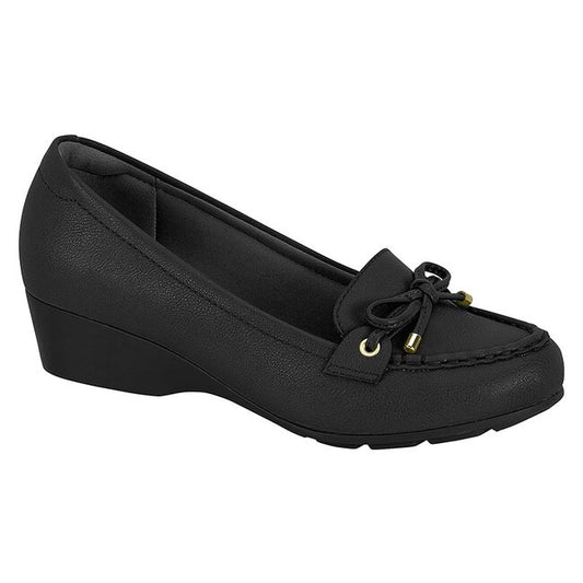 Product shot of a black wedge loafer with gold accents and a subtle bow detail showcasing a textured upper and a slightly chunky sole
