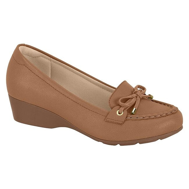 Product shot of a light brown women's wedge loafer featuring a bow detail gold accents and a textured finish
